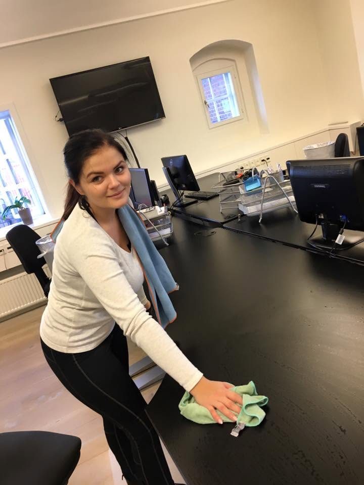 Medarbejder tørrer skrivebord af på kontor
